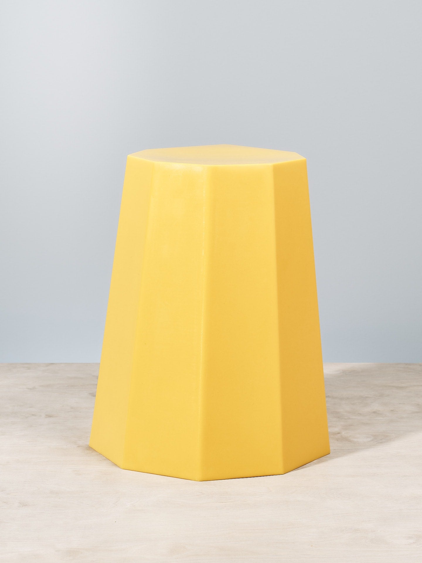 An Arnold Circus Stool – Yellow by Martino Gamper sitting on top of a wooden table.