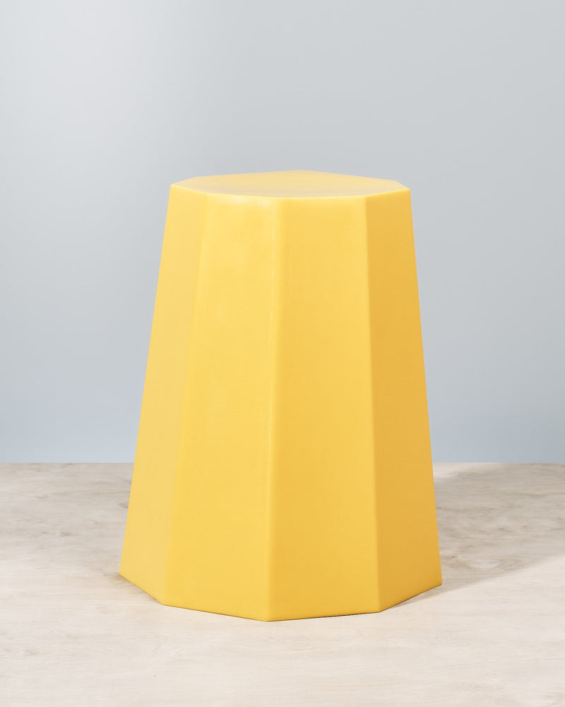 An Arnold Circus Stool – Yellow by Martino Gamper sitting on top of a wooden table.