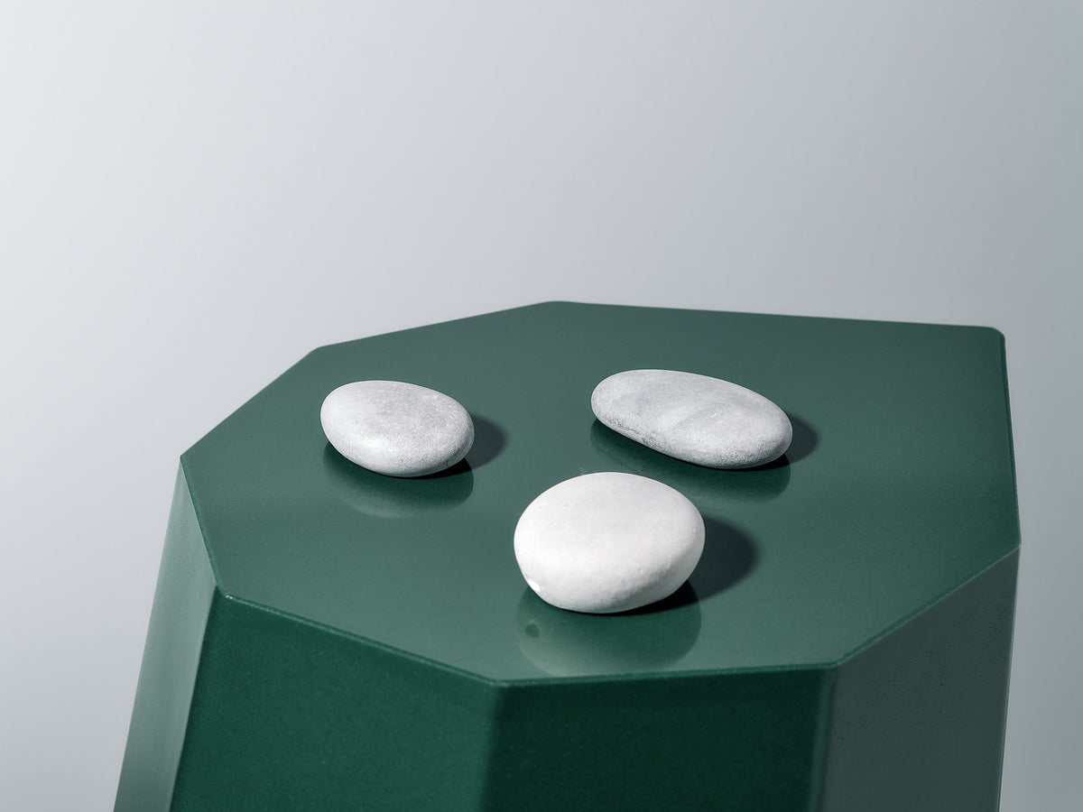 A Martino Gamper Arnold Circus Stool – Forest with three stones on top.
