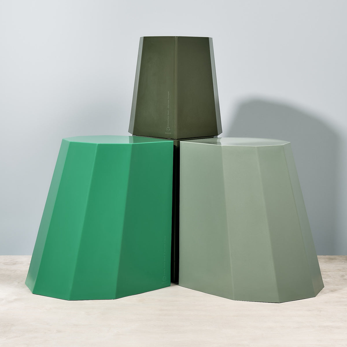 Three Arnold Circus Stools - Sage by Martino Gamper on a wooden table.