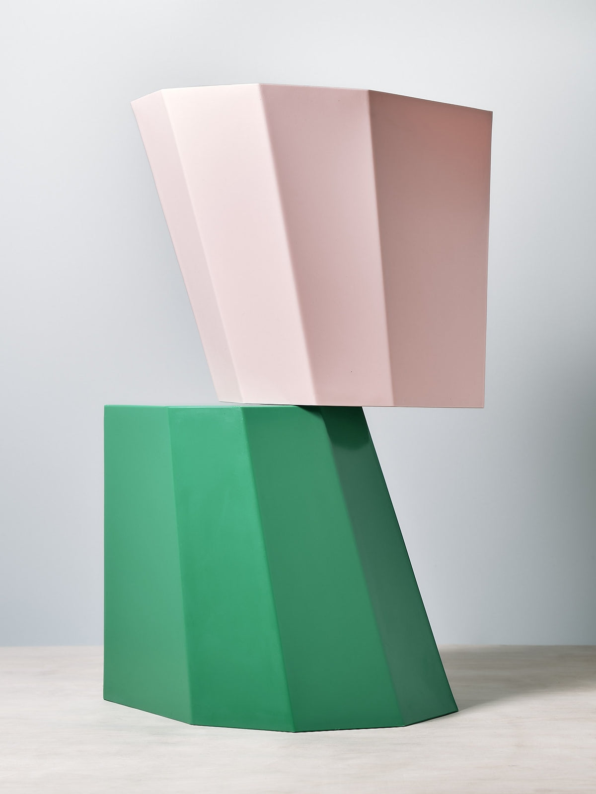 Two pink and green Arnoldino Stools by Martino Gamper on top of a table.