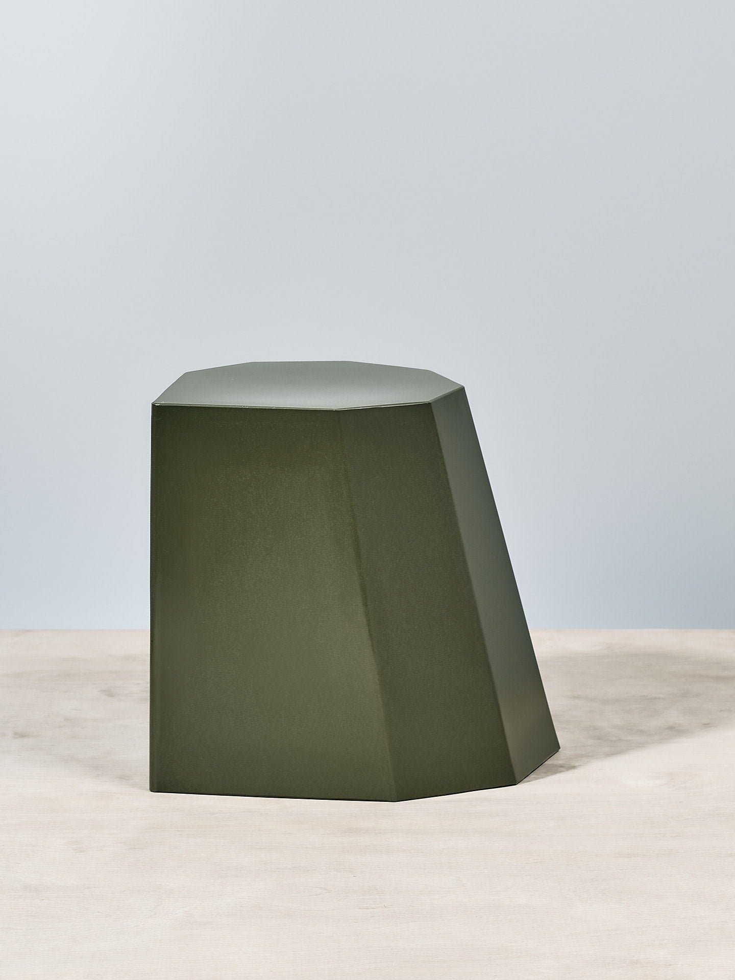 An Arnoldino Stool – Khaki by Martino Gamper on top of a wooden table.