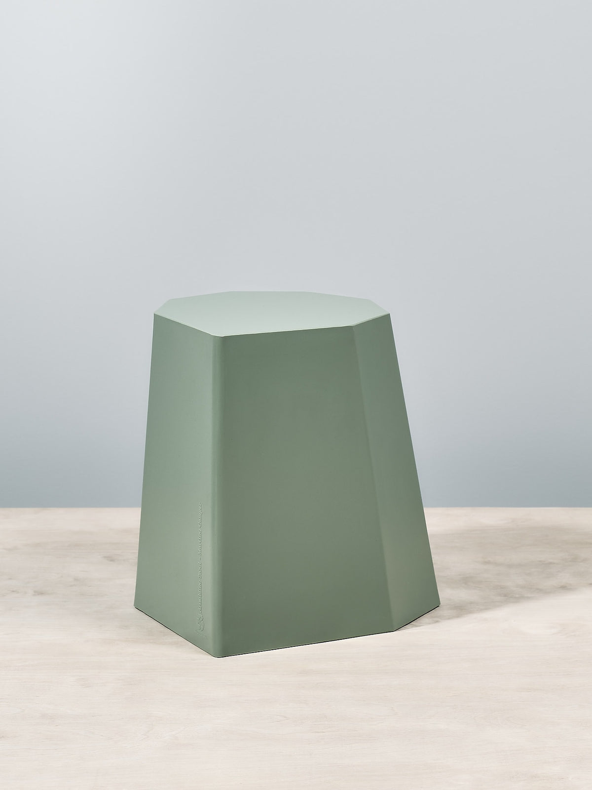 An Arnoldino Stool – Sage by Martino Gamper sitting on top of a table.