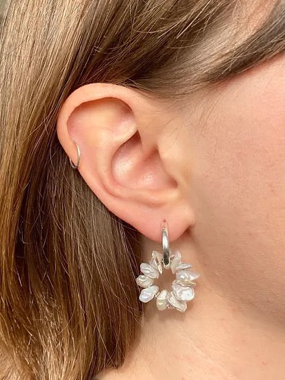 A woman&#39;s ear with a Coral Sleepers earring from Avara Studio.
