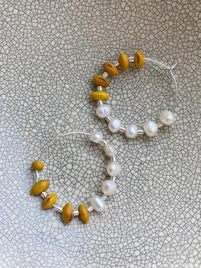 A pair of Kōwhai + Pearl Hoops by Avara Studio.