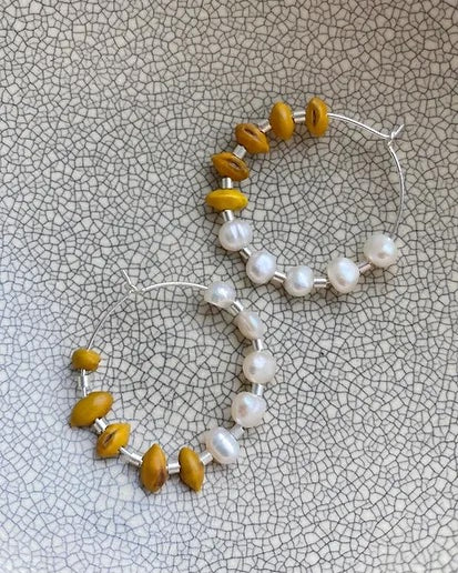 A pair of Kōwhai + Pearl Hoops by Avara Studio.