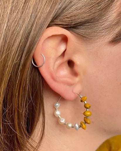 A woman's ear with a Kōwhai + Pearl Hoops earring by Avara Studio.