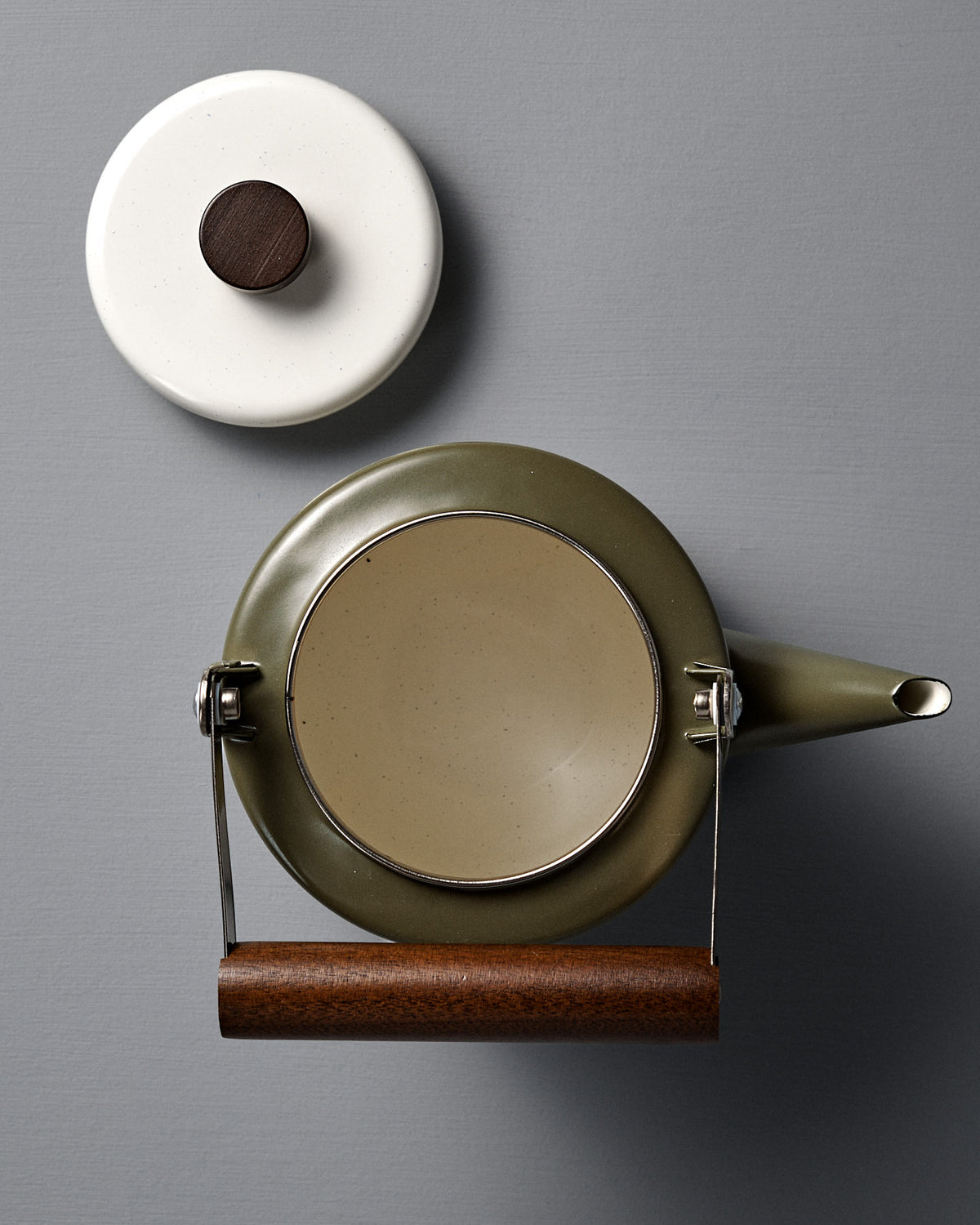 Top-down view of the Enamel Two-Tone Kettle – Olive Drab with a green finish and walnut handle, its matching lid set beside it on a gray surface.