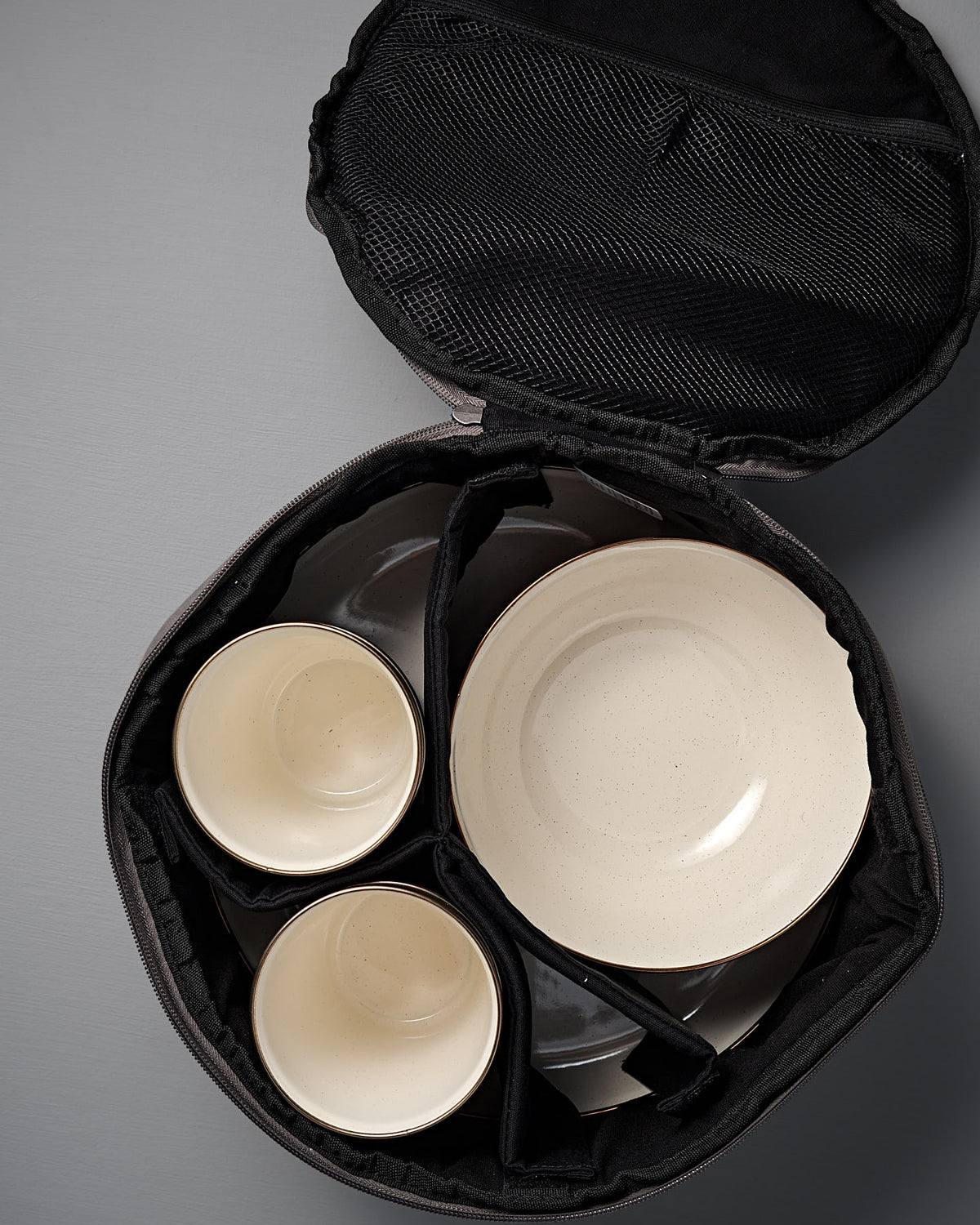 The Barebones Padded Utility Storage Bag features a black interior and padded dividers to securely hold two bowls and two plates—perfect for storing your Barebones enamelware.