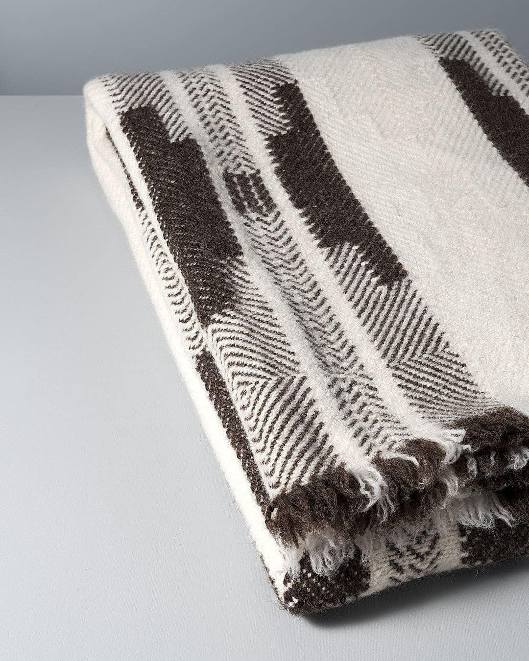 A **Rodopska Takan Bulgarian Shevitza Wool Blanket – Cream,** crafted from locally sourced wool and inspired by traditional Bulgarian shevitza, lies on a gray surface.