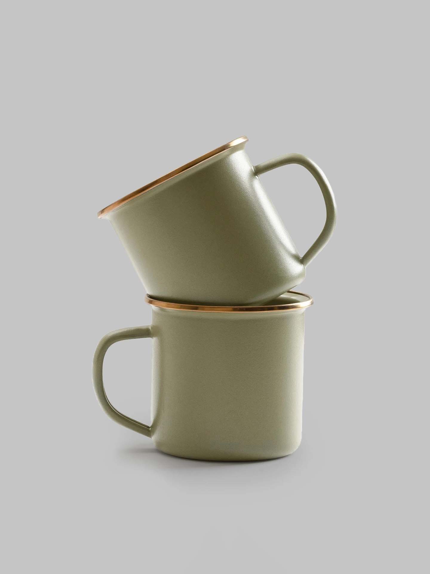 A pair of Barebones Enamel Two-Tone Mugs in olive drab are stacked together against a simple gray background, evoking a classic enamelware design.