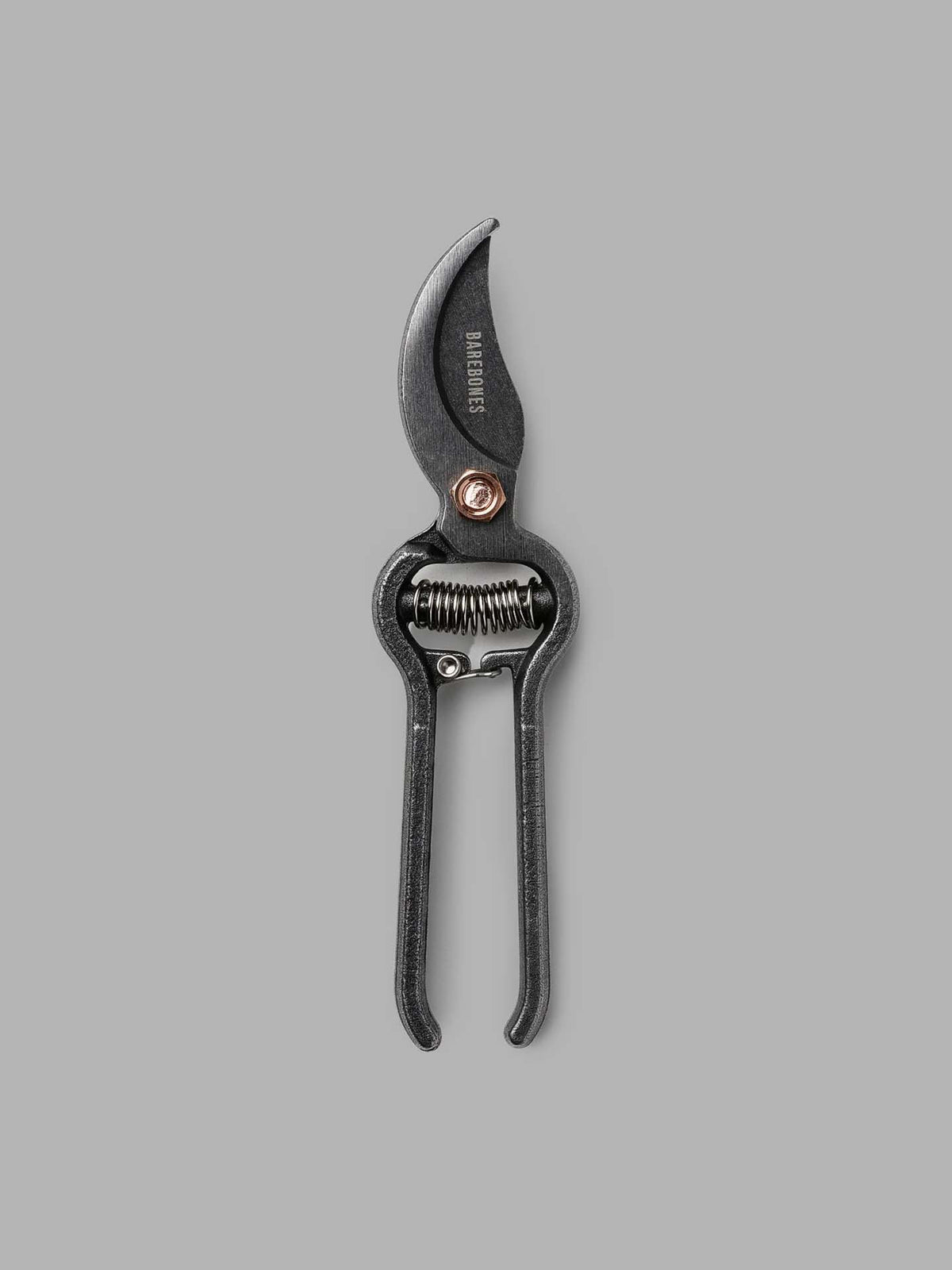 The Pruner with sheath by Barebones showcases a robust steel construction, embracing Japanese design aesthetics as black metal garden shears set against a gray background and incorporating a practical spring mechanism.