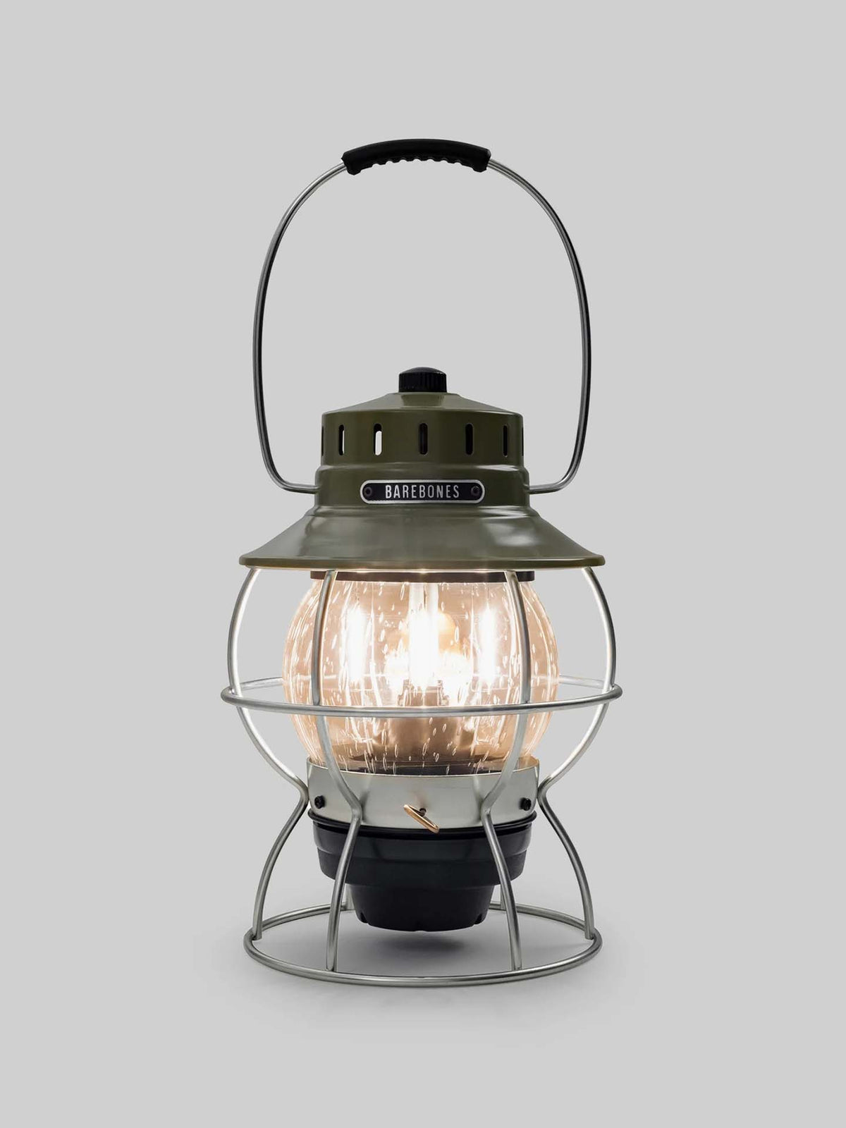 The Railroad Lantern – Olive Drab by Barebones, showcasing an Edison-style LED bulb and a transparent glass globe with a vintage-style olive green top, is set against a plain gray background.