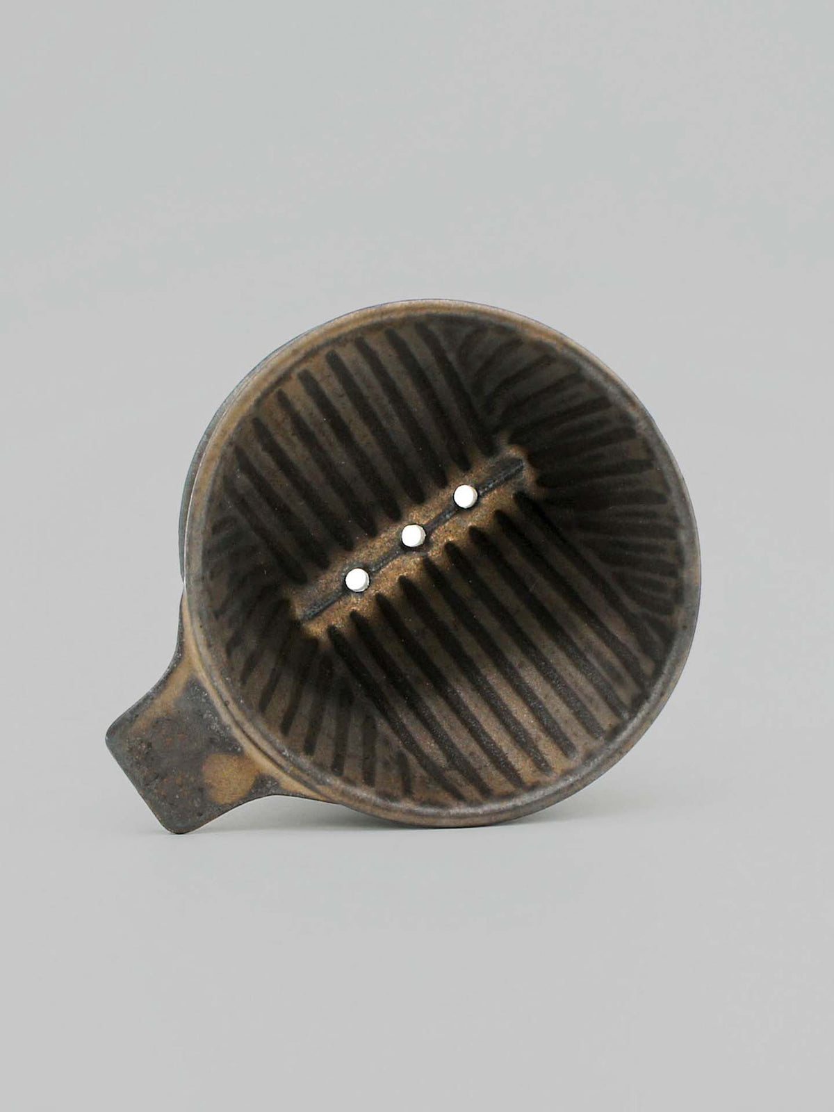 A Mino-yaki Coffee Dripper (2 Cup) – Brass by CHIPS Inc., featuring ribbed sides and three holes at the bottom, viewed from above, captures the artistry of ancient pottery.