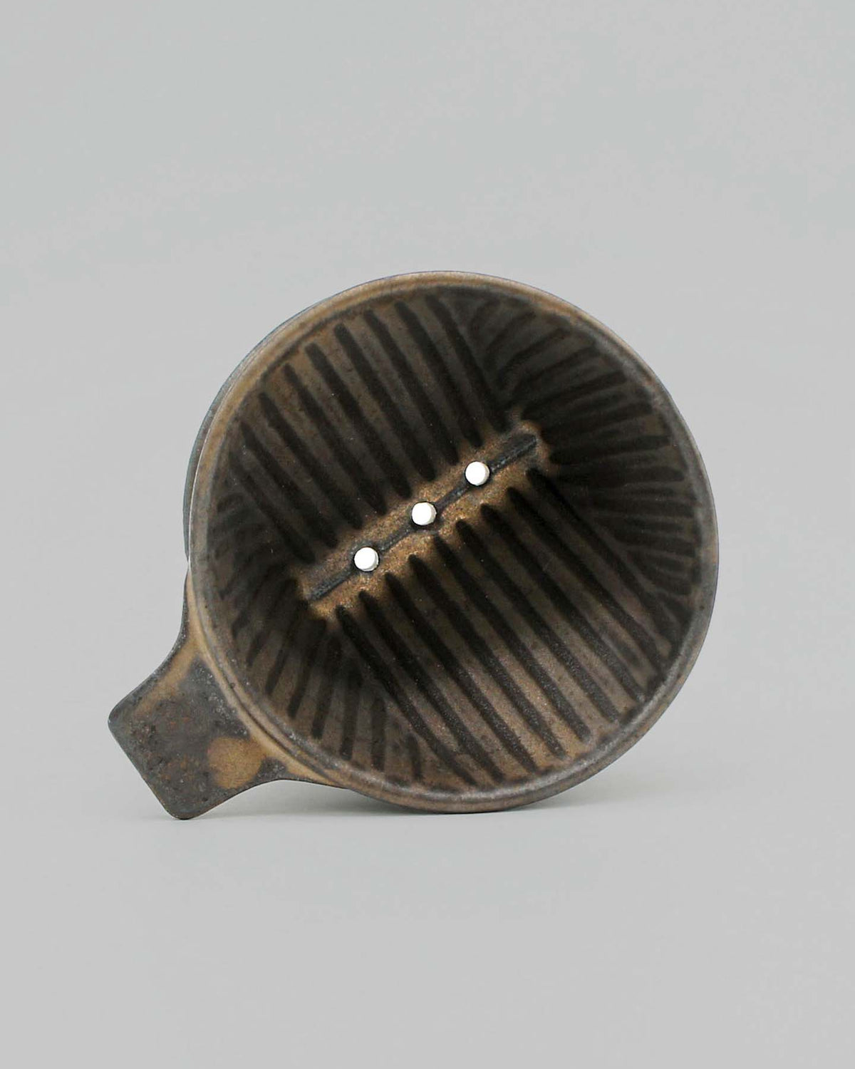 A Mino-yaki Coffee Dripper (2 Cup) – Brass by CHIPS Inc., featuring ribbed sides and three holes at the bottom, viewed from above, captures the artistry of ancient pottery.