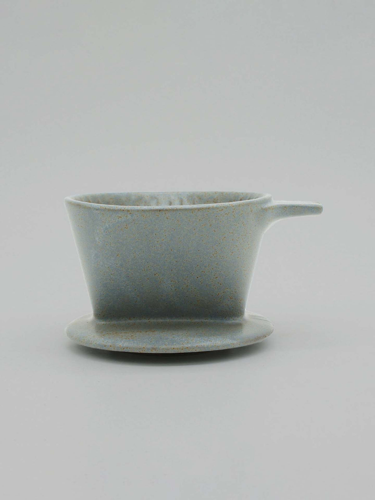 A minimalist gray ceramic coffee dripper from CHIPS Inc., inspired by the Mino-yaki tradition, sits elegantly on a matching saucer.