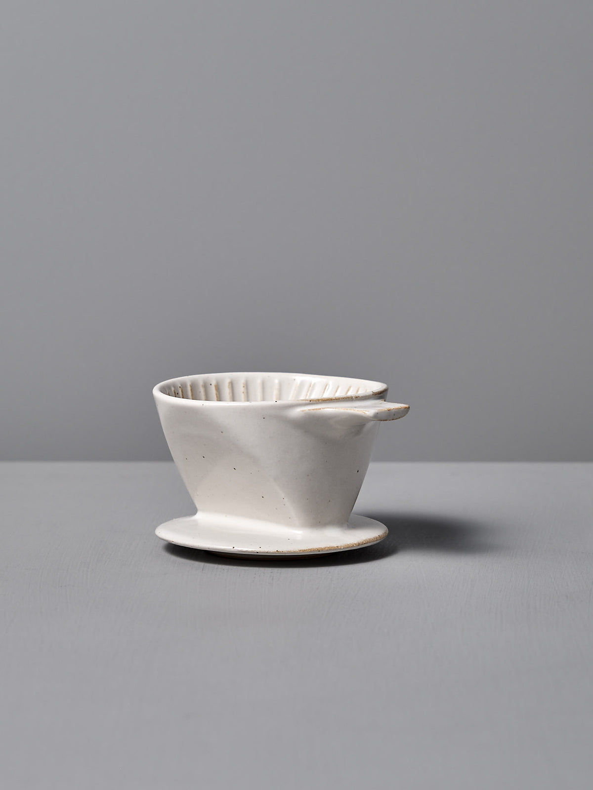 The CHIPS Inc. Mino-yaki Coffee Dripper (2 Cup) – White, a fine example of Japanese craftsmanship, elegantly rests on a gray surface against a matching backdrop.