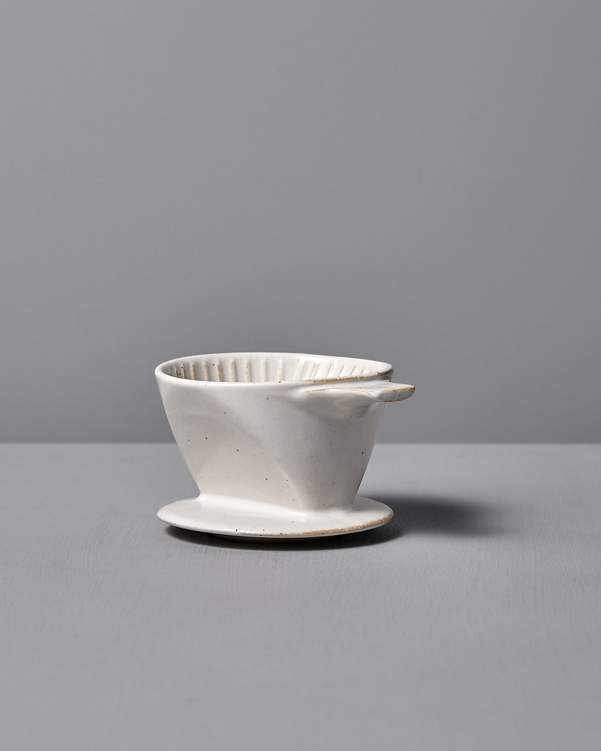 The CHIPS Inc. Mino-yaki Coffee Dripper (2 Cup) – White, a fine example of Japanese craftsmanship, elegantly rests on a gray surface against a matching backdrop.