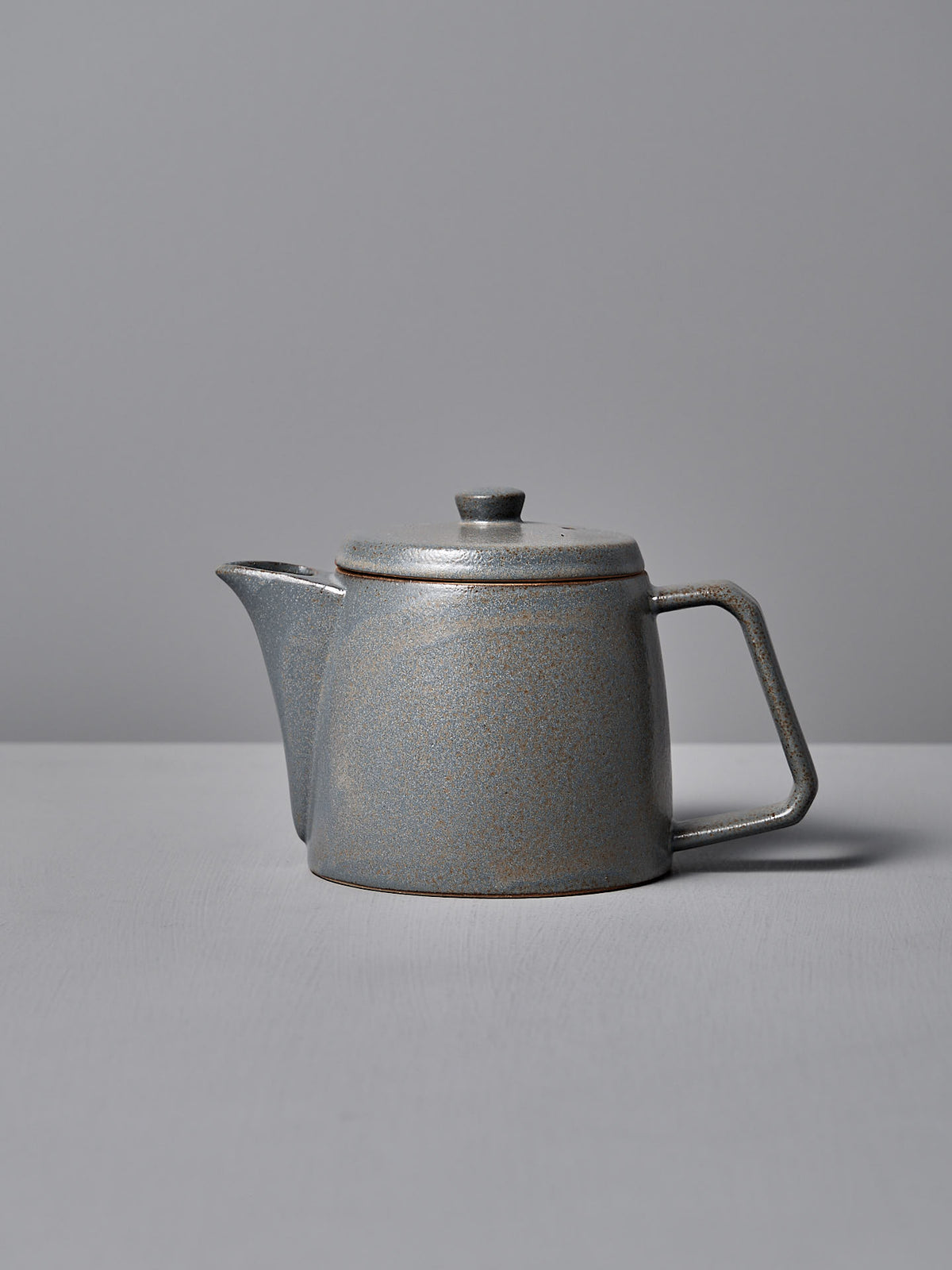 The Mino-yaki Teapot (2 Cup) – Grey by CHIPS Inc. features a modern, angular handle and smooth finish, crafted using the traditional Mino-yaki technique, set against a light gray background.