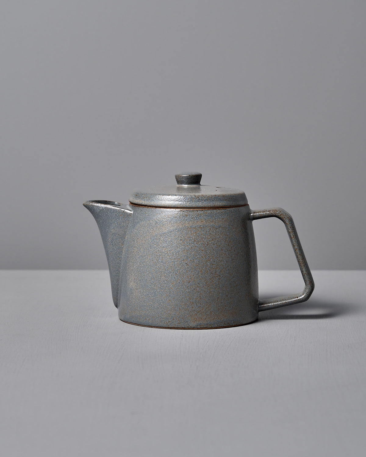 The Mino-yaki Teapot (2 Cup) – Grey by CHIPS Inc. features a modern, angular handle and smooth finish, crafted using the traditional Mino-yaki technique, set against a light gray background.
