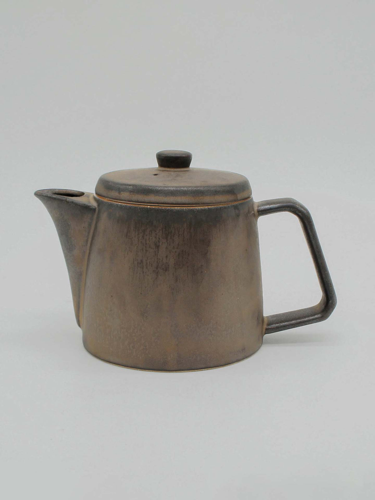 The Mino-yaki Teapot (2 Cup) – Brass by CHIPS Inc. is a rustic, matte-finish ceramic teapot crafted using the Mino-yaki technique. It features a cylindrical body, an angled spout, a lid, and a rectangular handle. Ideal for brewing loose leaf tea, it&#39;s presented against a simple, light background.