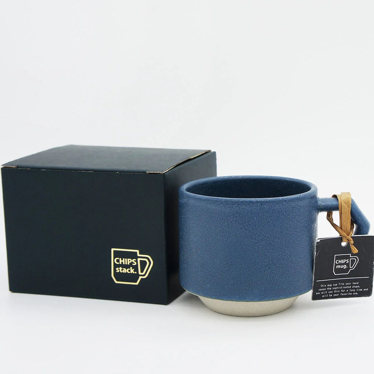 A CHIPS Inc. stackable blue ceramic mug with a tag in front of a box.