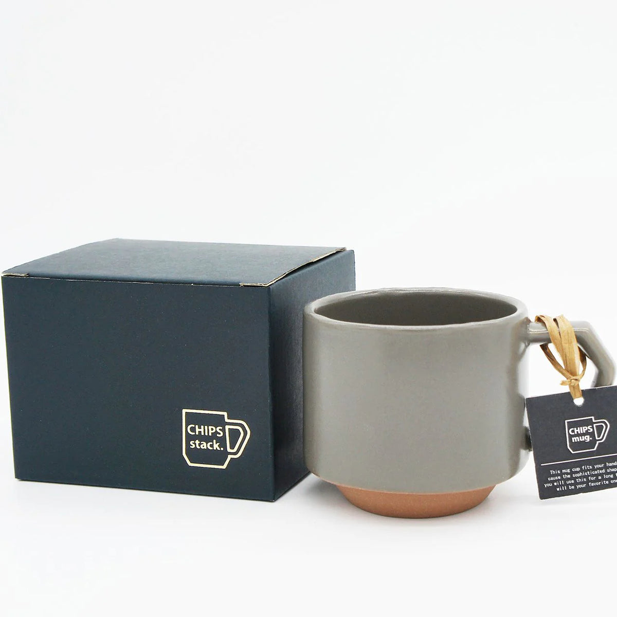 A Stacking Mug - Khaki with a tag in front of a stackable box.