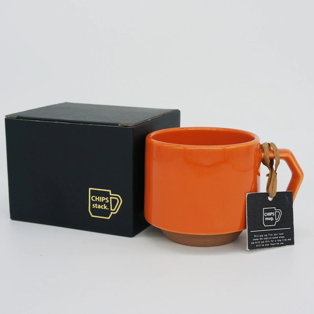 A Stacking Mug - Orange with a black tag made by CHIPS Inc.