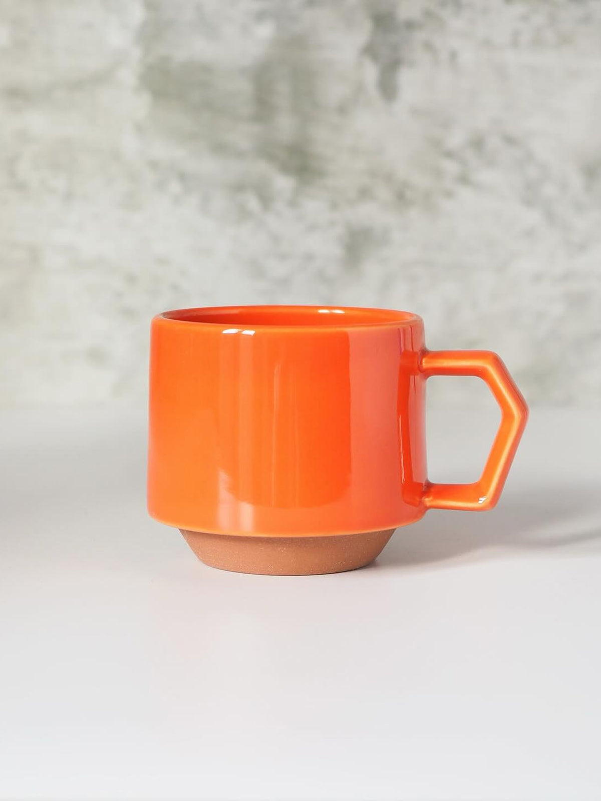 A CHIPS Inc. Stacking Mug – Orange with a handle on it.