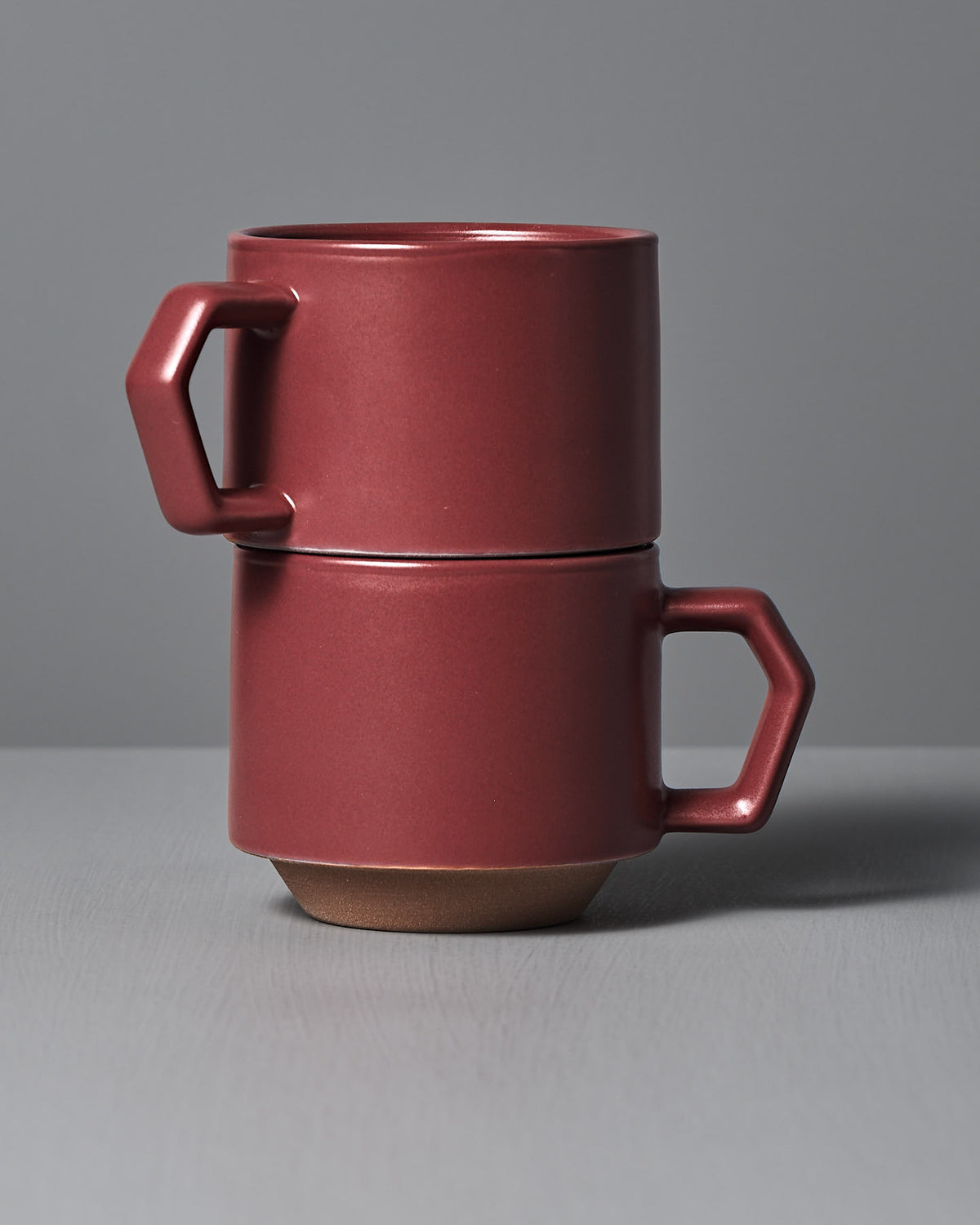 Two Stacking Mug – Matte Red by CHIPS Inc. stacked against a gray background, showcasing angular handles and a modern design.