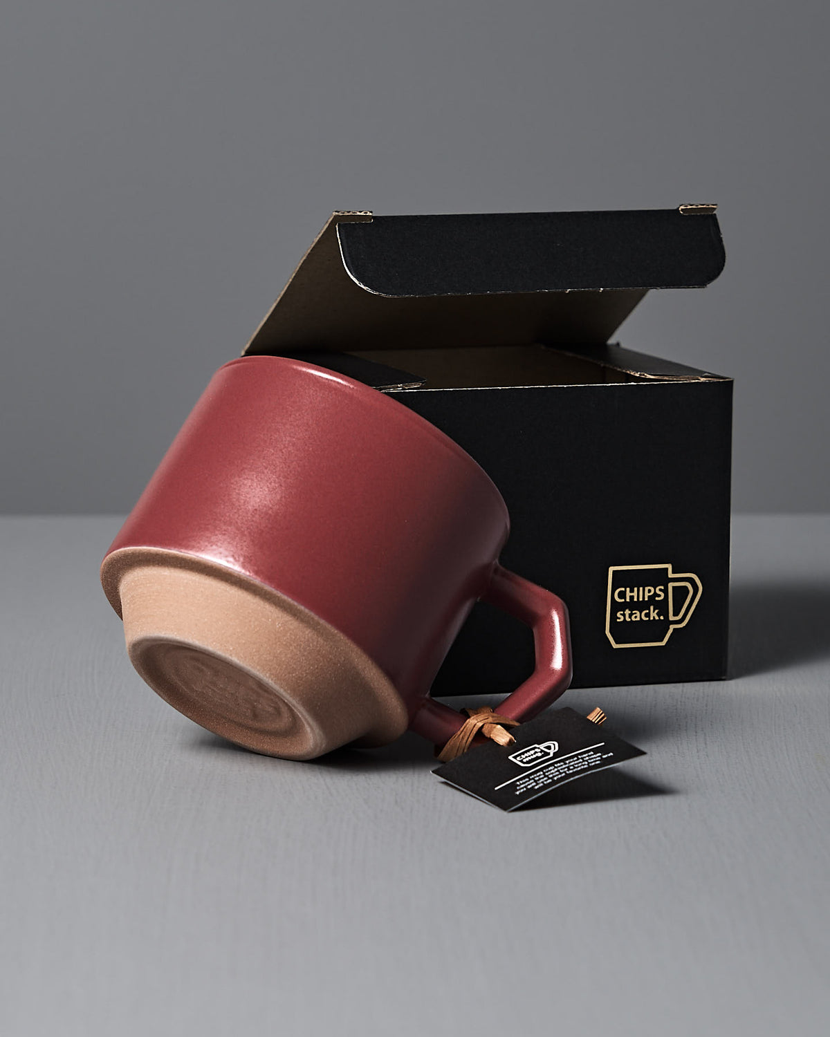 A Stacking Mug – Matte Red, made of Minoyaki porcelain, sits by an open CHIPS Inc. "CHIPS stack" black box. A black tag on the handle highlights its quality.