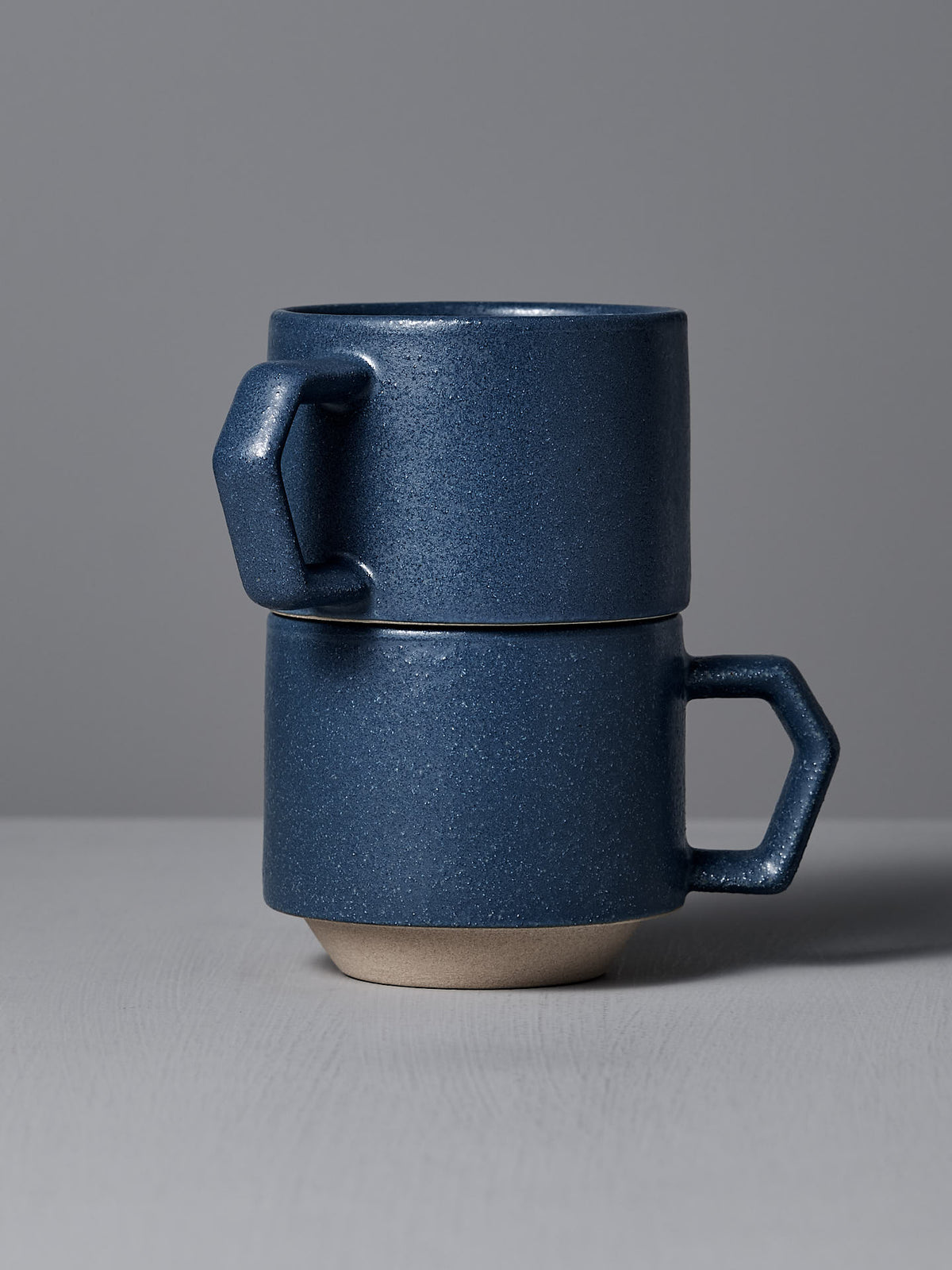 A pair of Stacking Mugs – Navy from CHIPS Inc. is elegantly displayed on a light gray surface.