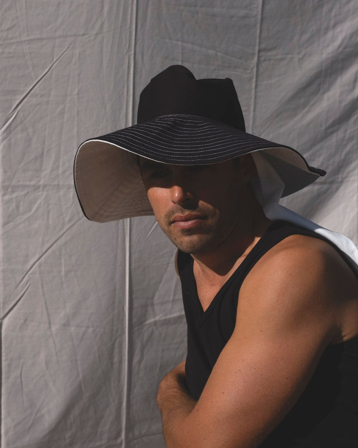 A man wearing a Companion Broad Brim with Wide Ties - Monochromatic hat for shade and protection.