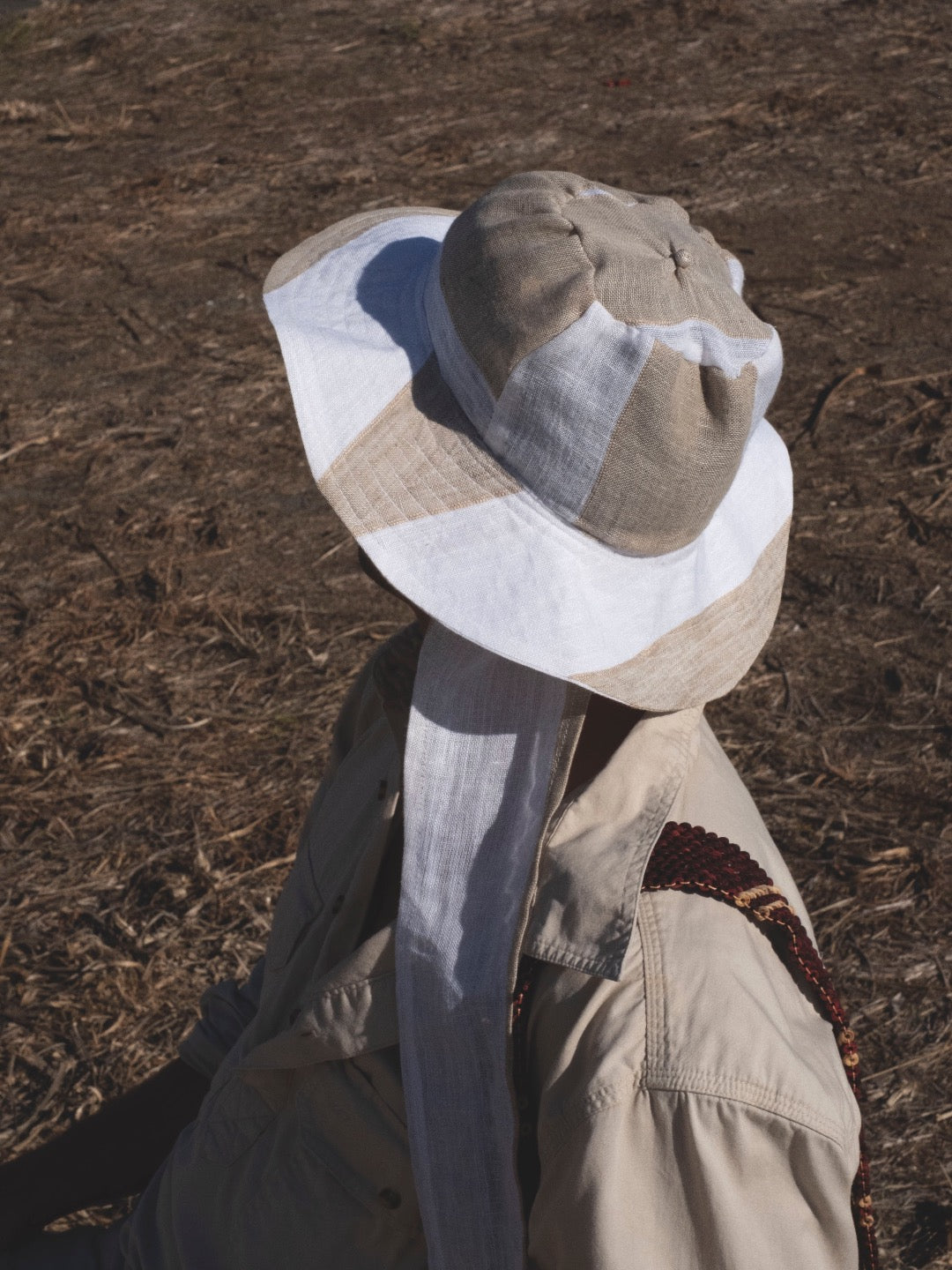 A man in a Companion hat, an essential summer staple, sitting in a field.