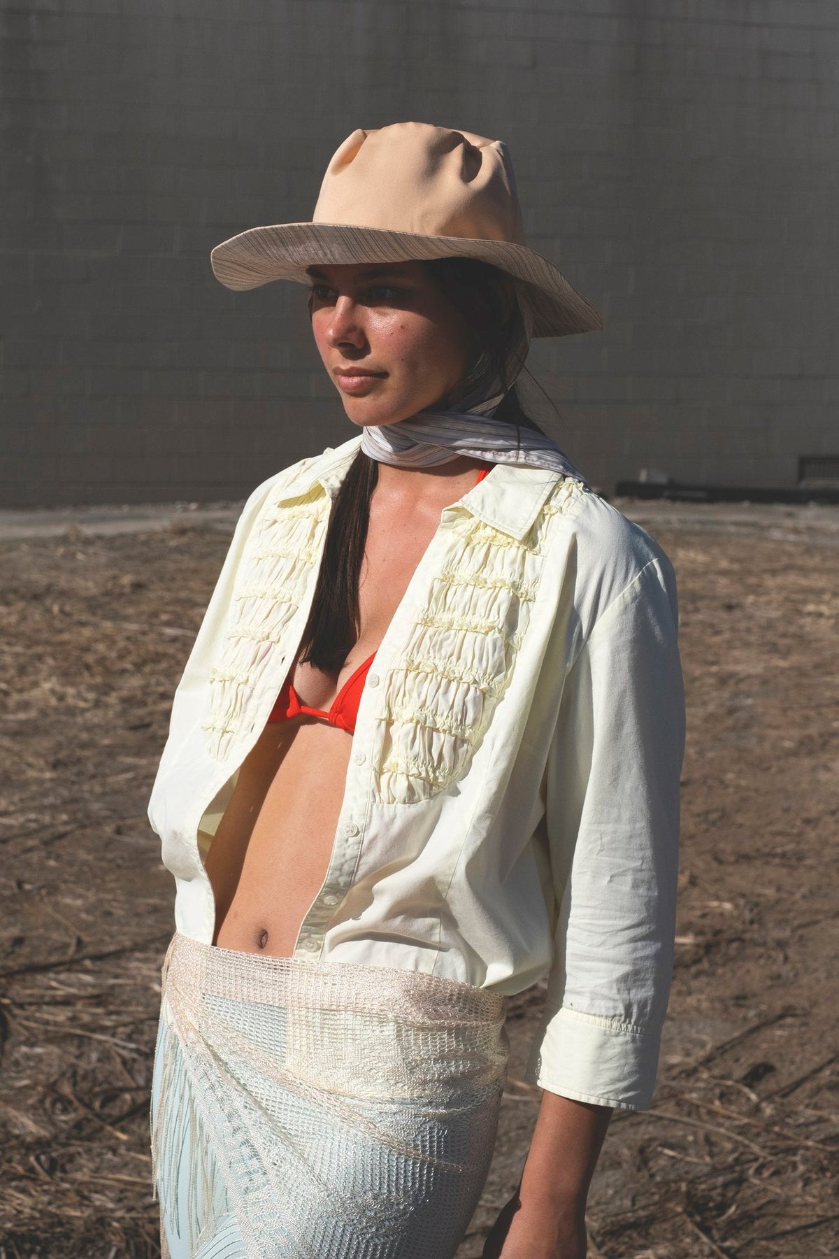 A woman in a Classic Brim with Wide Ties – Peach &amp; Stripe hat, by Companion, standing in a dirt field.