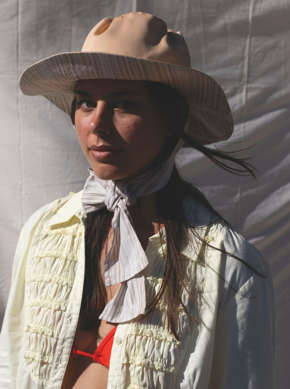 A woman in a Companion Classic Brim with Wide Ties – Peach &amp; Stripe hat and bikini posing for a photo, showcasing summer staple fashion with a touch of recycled textiles.