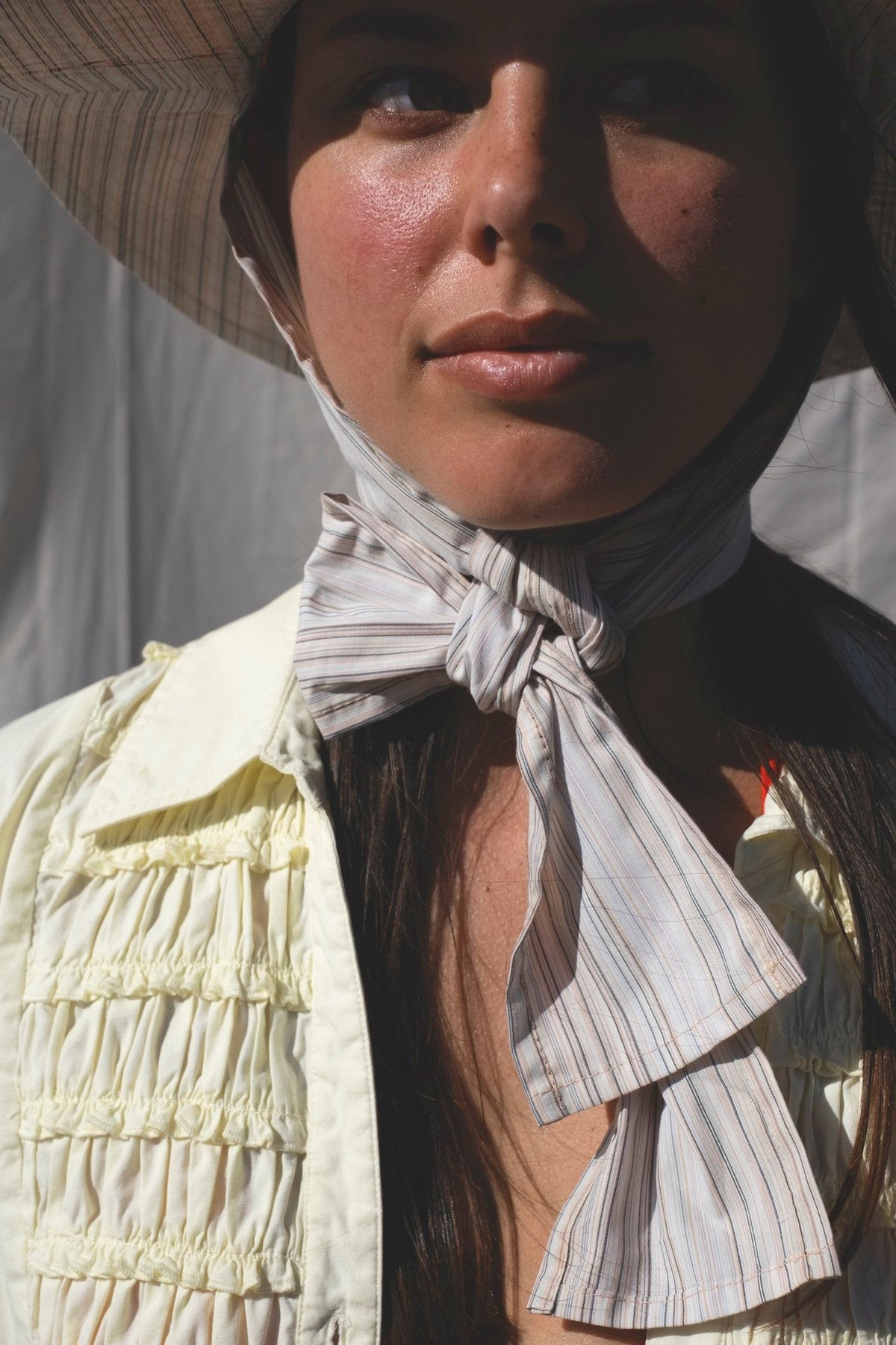 A woman wearing a Companion Classic Brim with Wide Ties – Peach &amp; Stripe hat and scarf, made from recycled textiles, a summer staple.