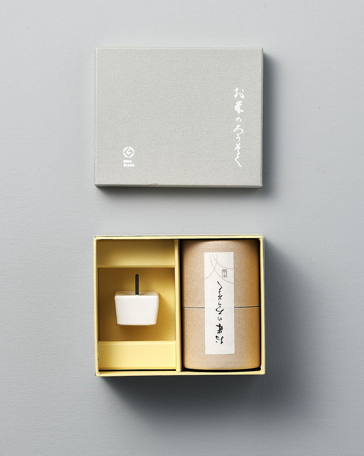 An open gift box set features a small white rice wax candle from the Daiyo brand and a cylindrical container adorned with Japanese text, all set against a light gray backdrop.