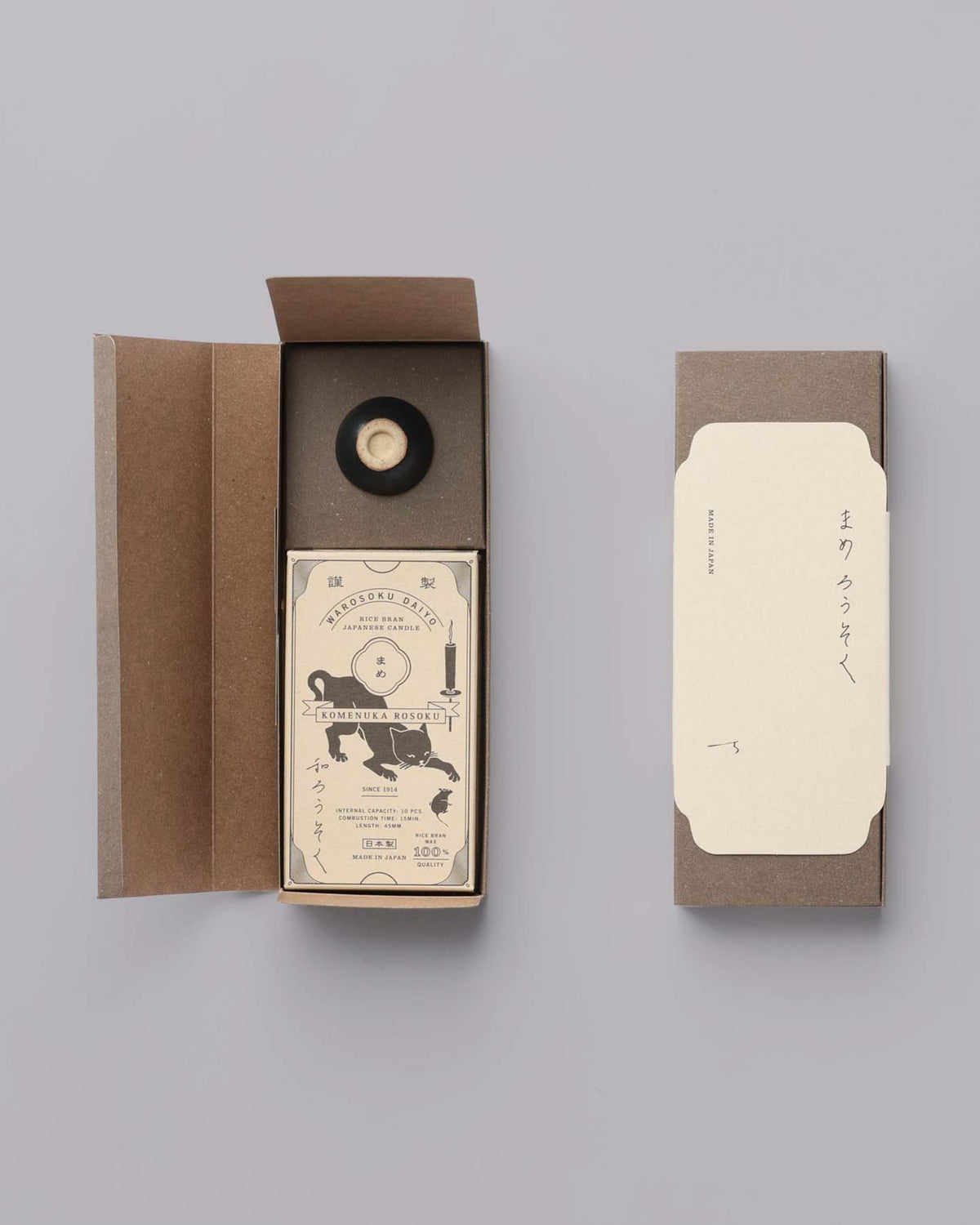Open the Daiyo Rice Wax Candle & Ceramic Stand Set – Earth | Black box to reveal a card and a sleek black ceramic stand that echo the serene elegance of Japanese candles. Adjacent, a closed box with white labeling adds to the minimalist design.