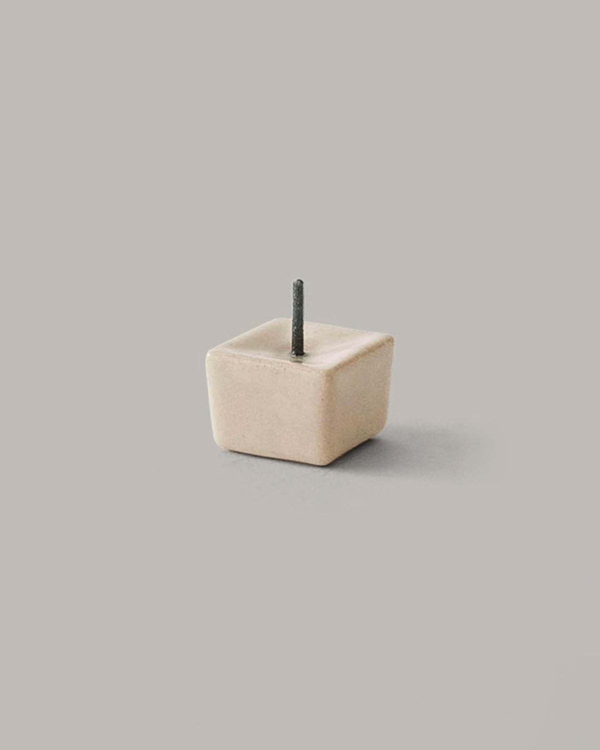 The Daiyo Rice Wax Candle & Iron Stand 20pc Box Set in Black, White, and Beige features a compact iron and ceramic candle stand with a square shape and a single short rod on top, beautifully showcased against a plain gray background.