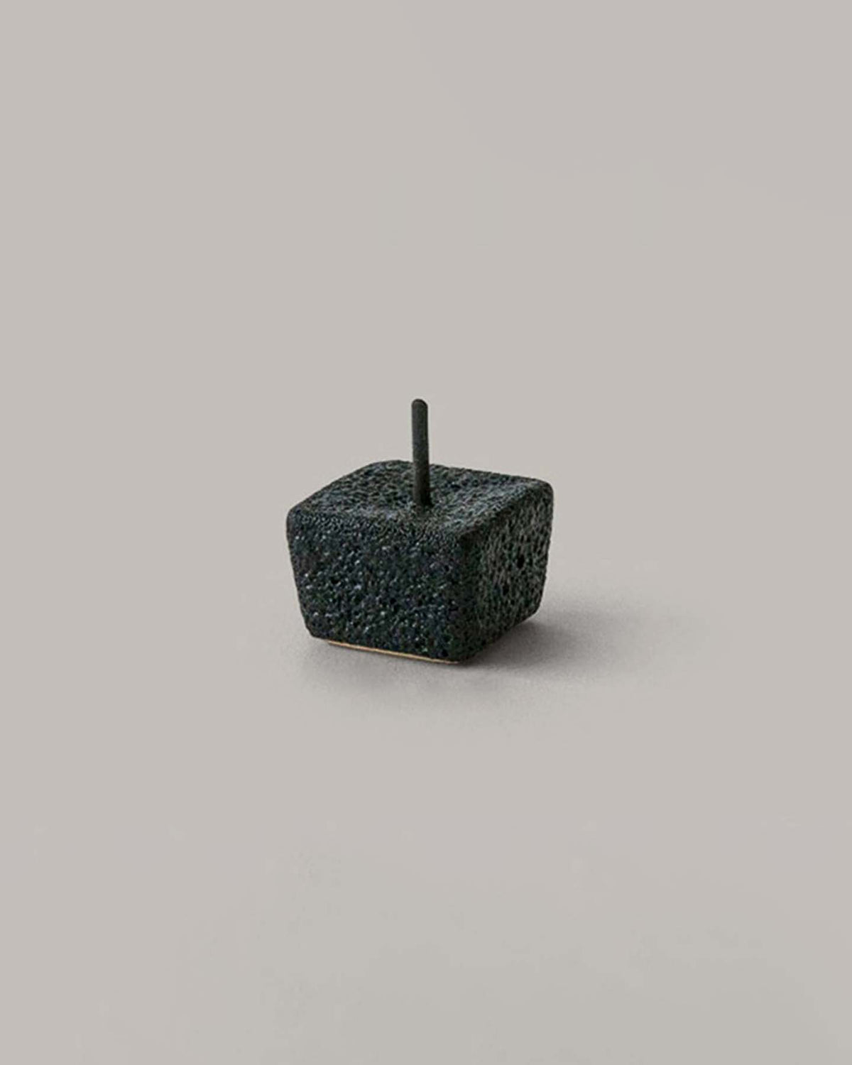 A minimalist, dark, cube-shaped incense holder with a single incense stick sits elegantly alongside Daiyo's refined Rice Wax Candle & Iron Stand 20pc Box Set in black, white, and beige, all against a neutral background.
