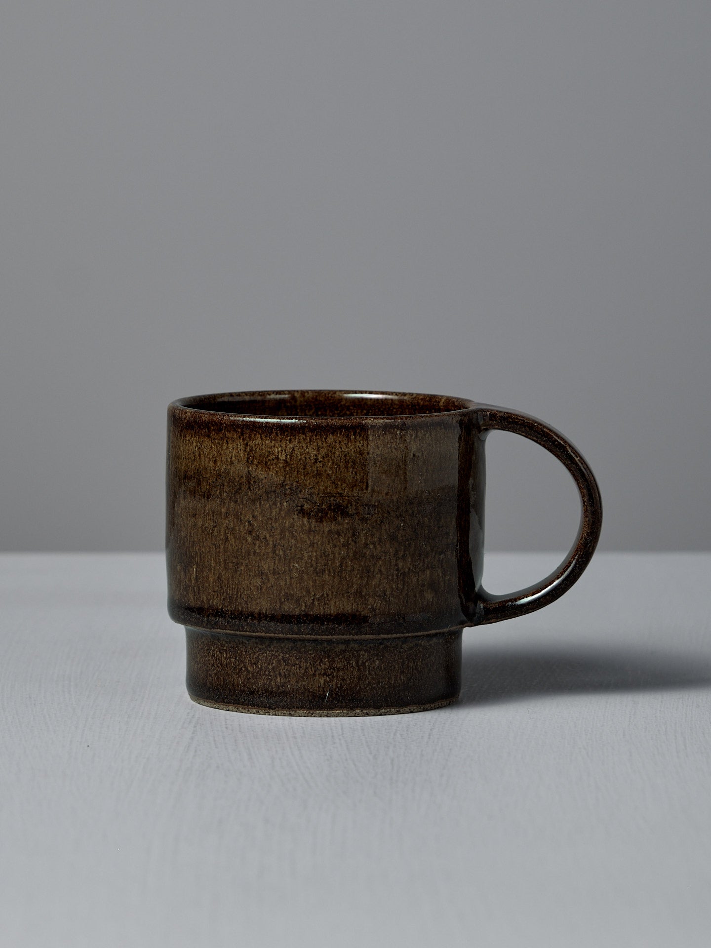 The Studio Foon Everyday Stacker Cup – Large in Burnt Umber rests on a light gray surface against a plain gray background—a stylish 300ml cup perfect for daily use.