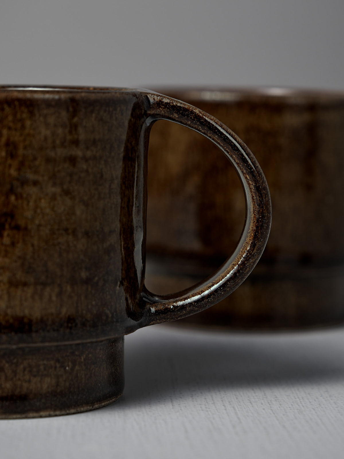 Close-up of two Studio Foon Everyday Stacker Cups – Large | Burnt Umber side by side, highlighting the handle of the 300ml cup in the foreground.