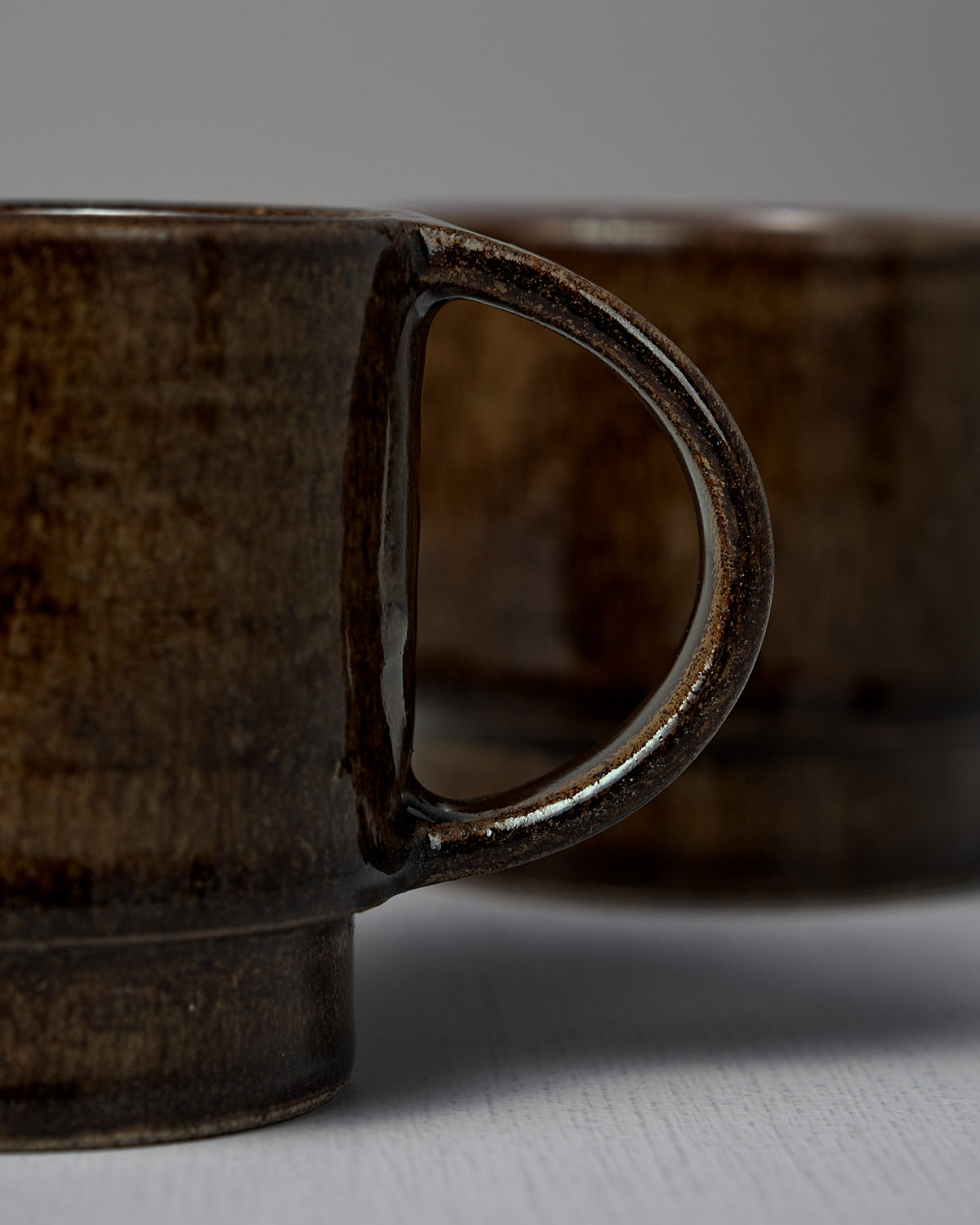 Close-up of two Studio Foon Everyday Stacker Cups – Large | Burnt Umber side by side, highlighting the handle of the 300ml cup in the foreground.