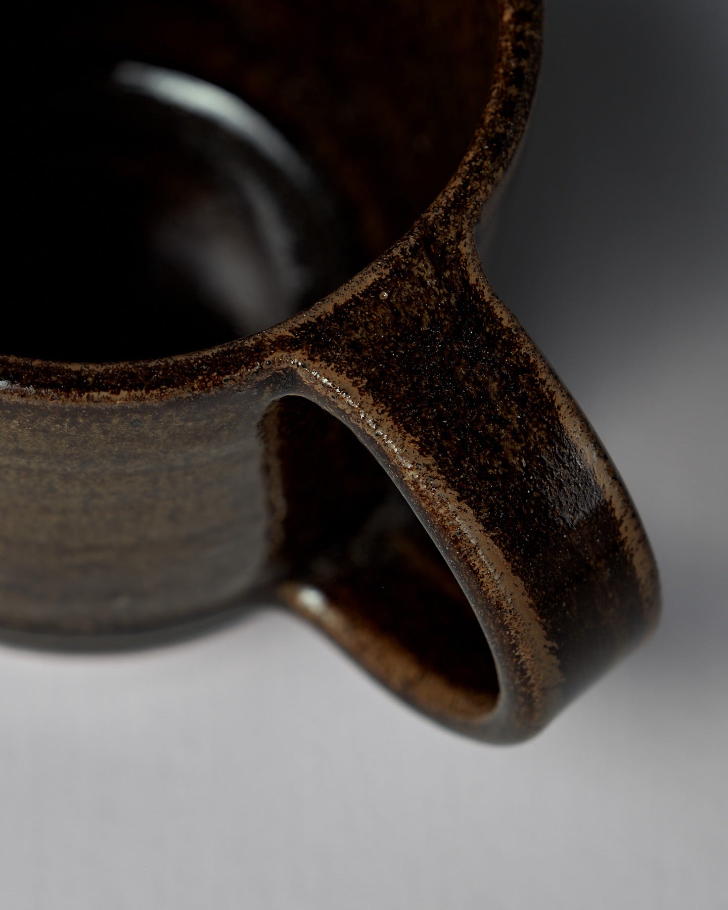 The Studio Foon Everyday Stacker Cup – Large in Burnt Umber, a handcrafted 300ml cup with a rounded handle, sits on a light gray surface against a plain gray background.