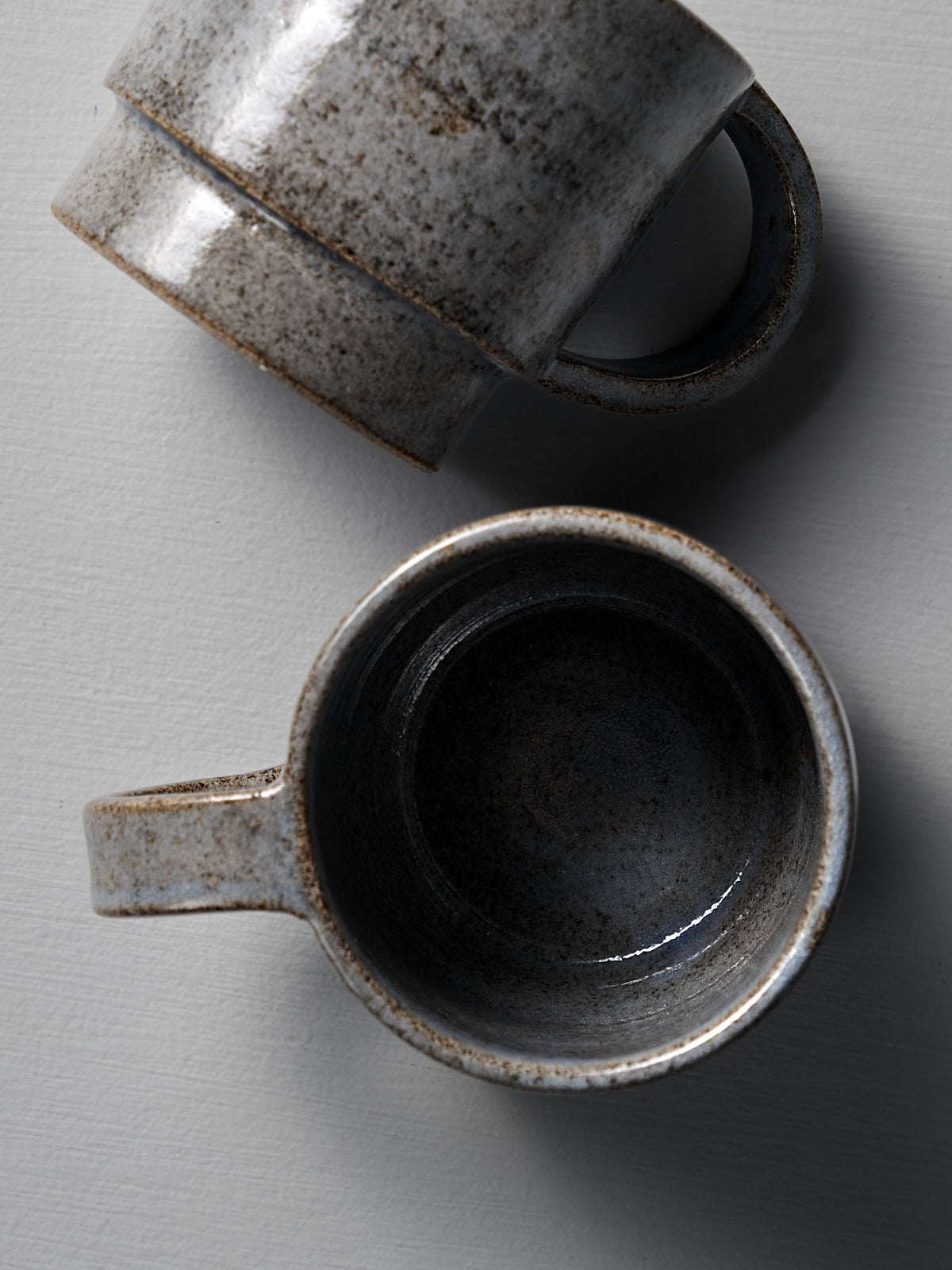 Two Everyday Stacker Cup – Large | Indigo mugs by Studio Foon, one upright and one on its side, display their charm as perfect everyday cups on a light textured surface.