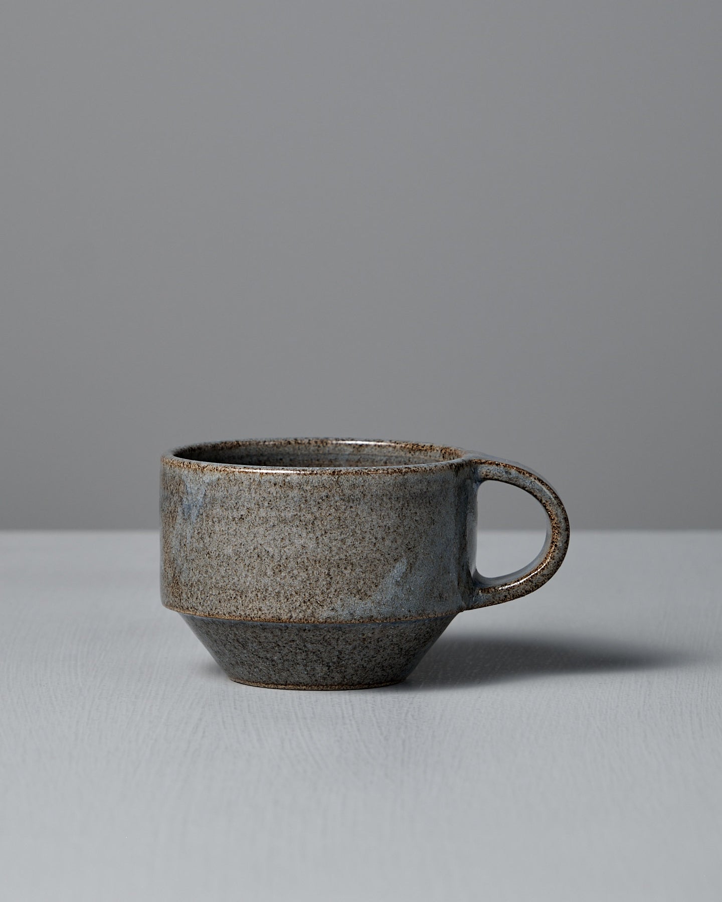 The Studio Foon Everyday Stacker Cup – Small in Indigo, featuring a handcrafted textured finish, rests on a light gray surface against a plain gray background.