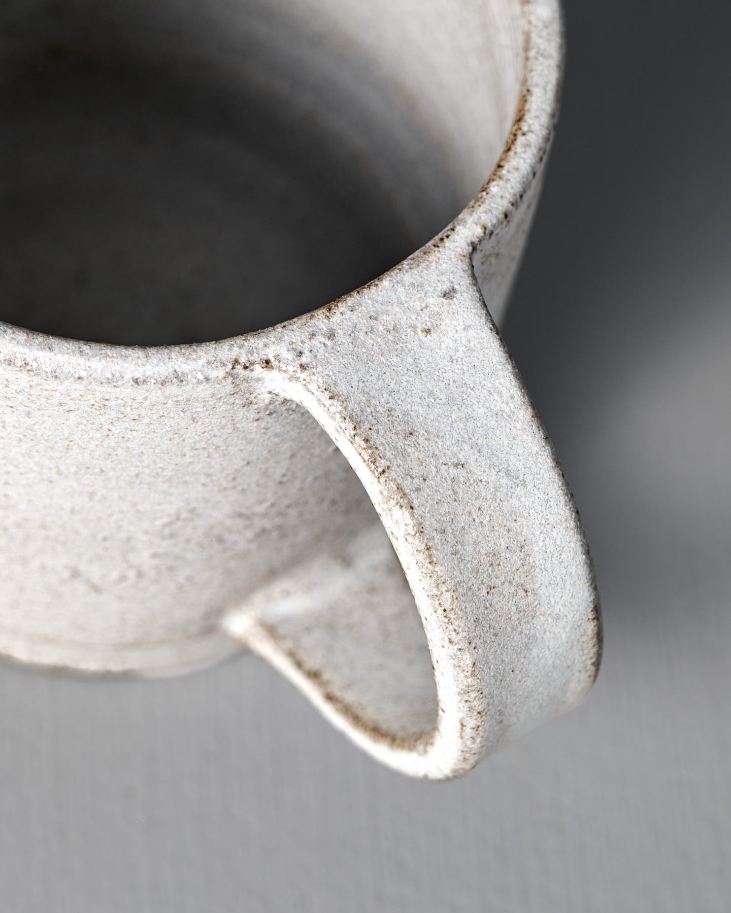The Studio Foon Everyday Stacker Cup – Large | Stone White is a handcrafted, speckled 300ml cup with a large handle. It’s perfect for daily use and pairs well with other stackable cups on any light gray surface.