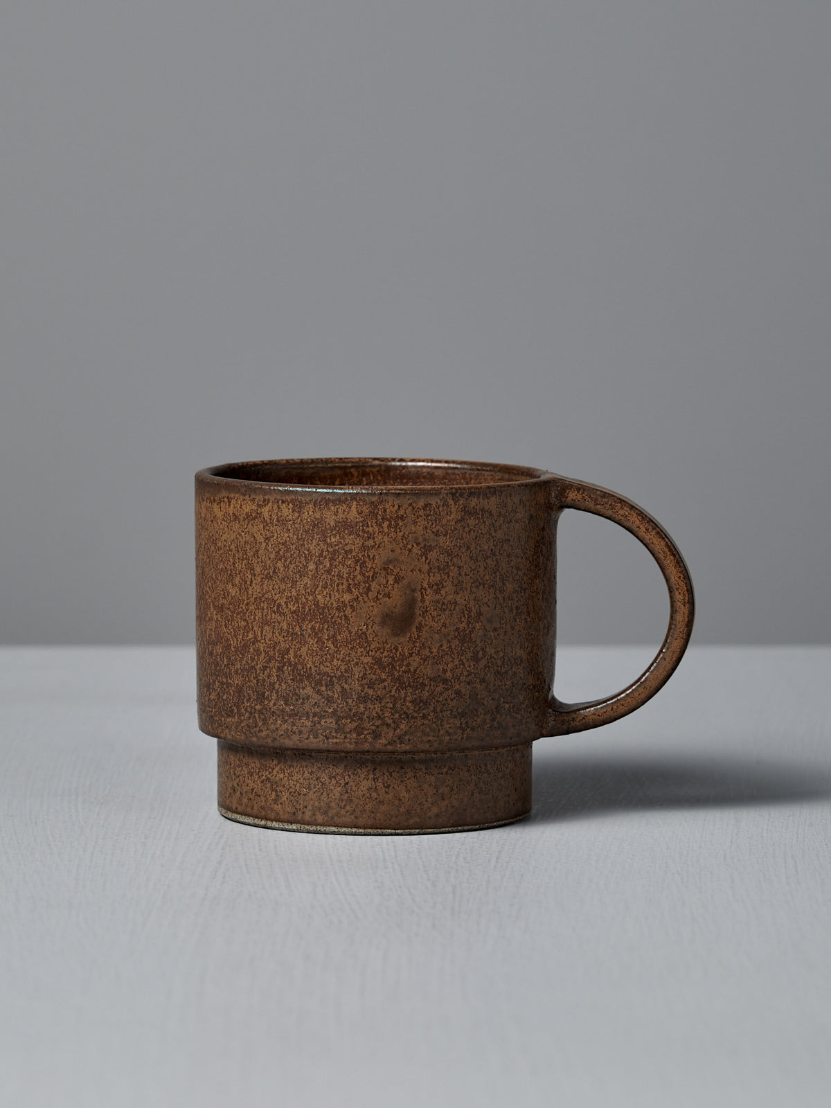 The Studio Foon Everyday Stacker Cup – Large in terracotta rests on a light gray surface with a plain gray background.