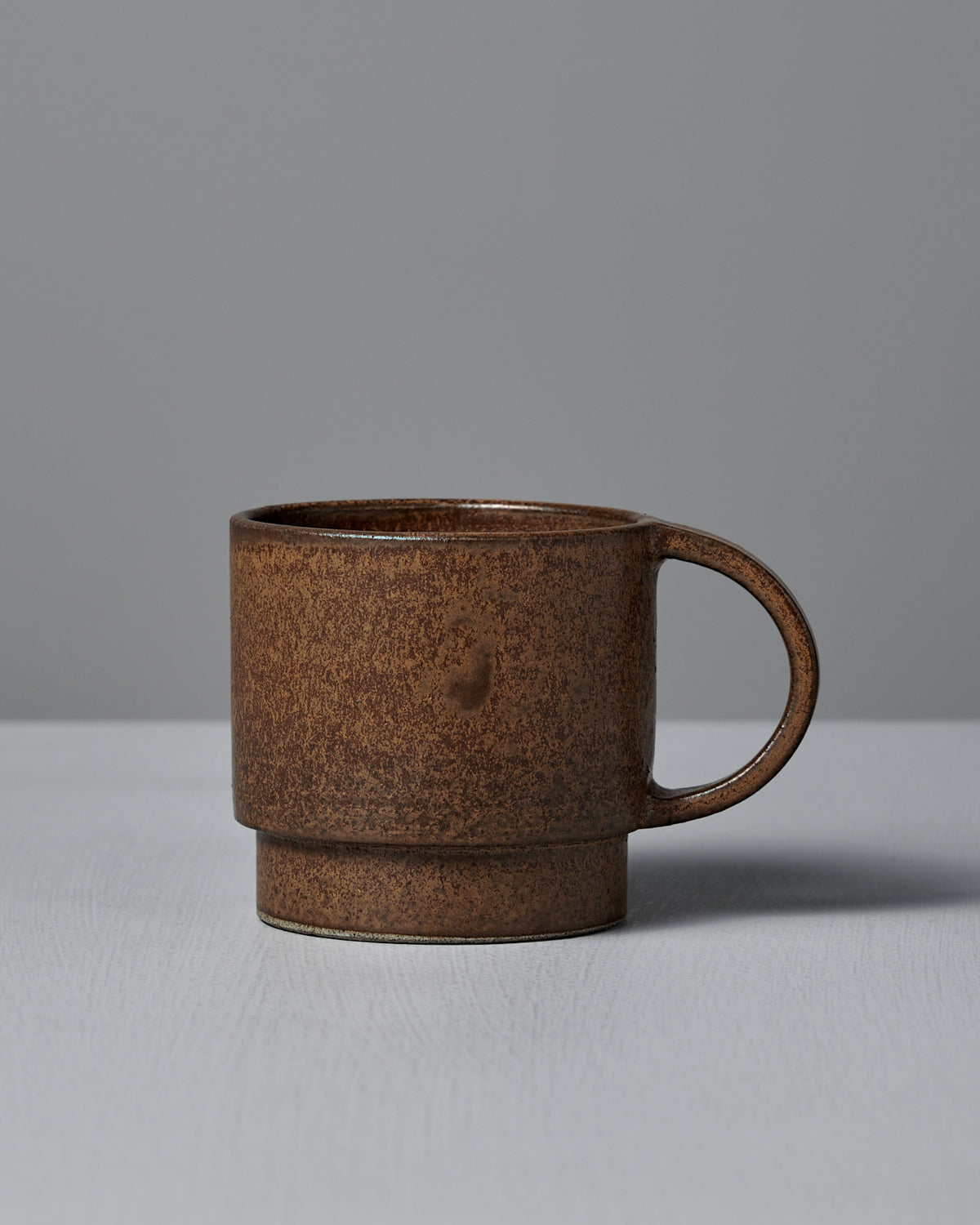 The Studio Foon Everyday Stacker Cup – Large in terracotta rests on a light gray surface with a plain gray background.